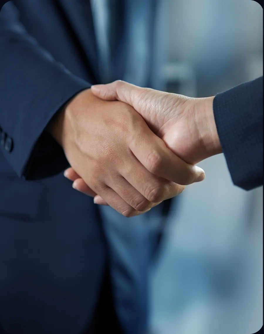 Aperto de mãos entre dois profissionais de terno, representando parceria e confiança