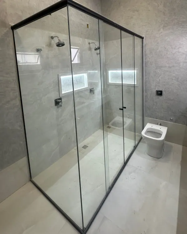 Box de vidro temperado com perfis pretos em banheiro amplo de porcelanato