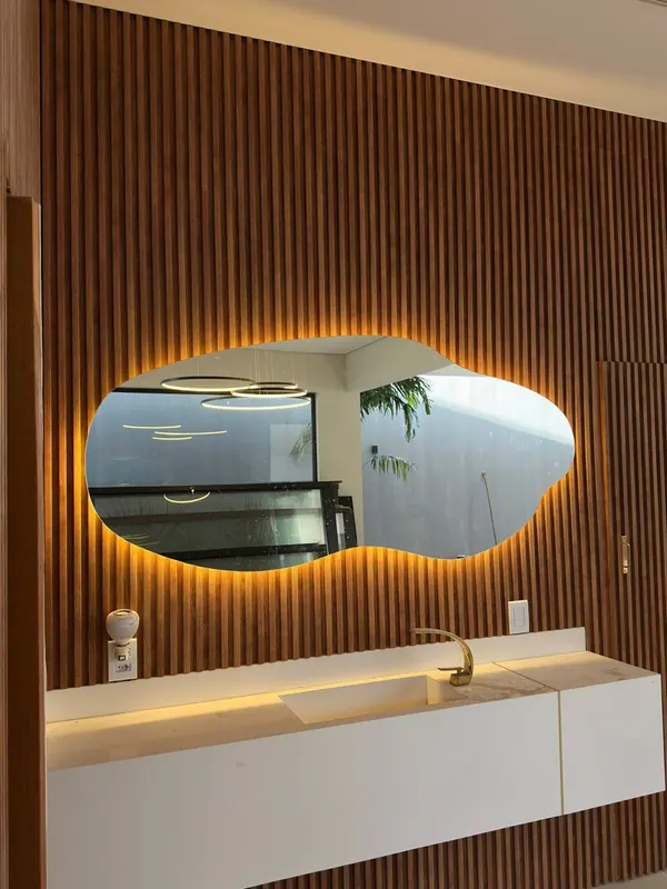 Espelho orgânico com iluminação LED em lavabo com painel ripado de madeira
