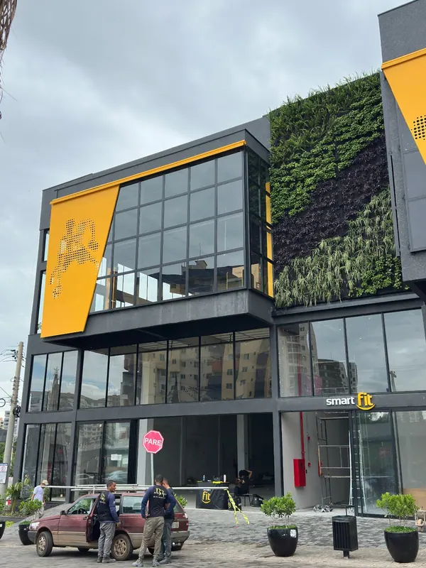 Fachada comercial em pele de vidro com jardim vertical