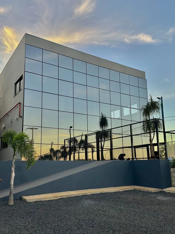 Fachada em pele de vidro espelhado de prédio comercial ao pôr do sol