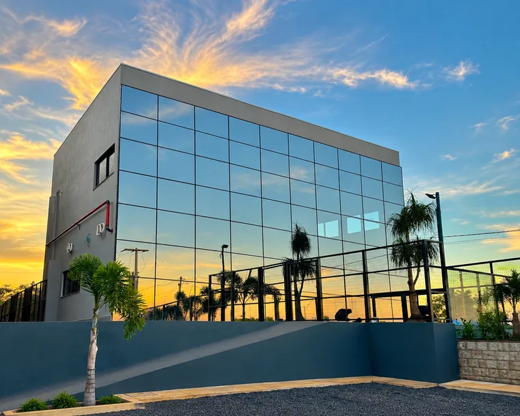 Fachada em pele de vidro espelhado de prédio comercial ao pôr do sol