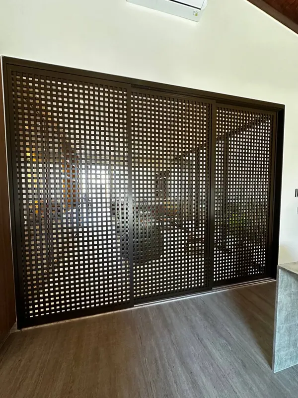 Painel deslizante de alumínio preto vazado separando ambientes