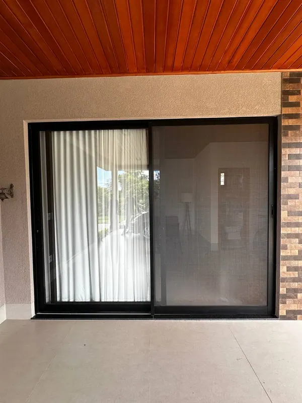 Porta de correr de vidro com perfis de alumínio preto na varanda