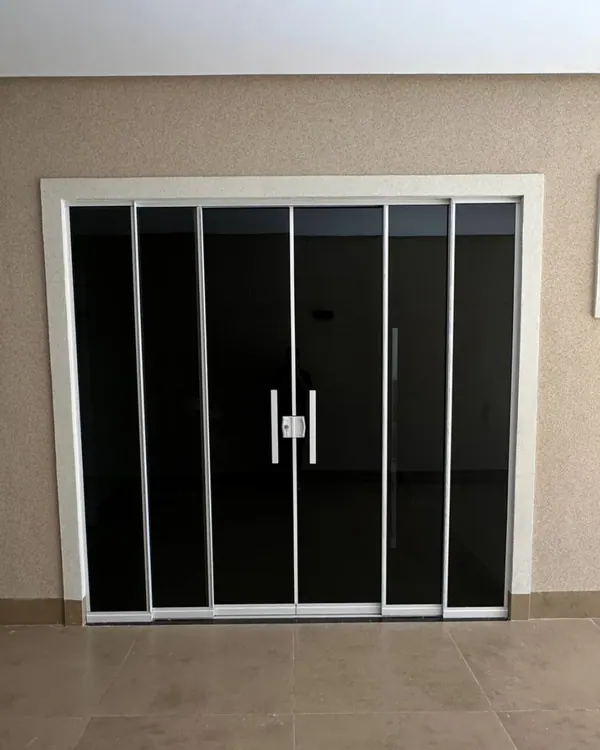 Porta de correr de vidro temperado fumê com quatro folhas e perfis brancos